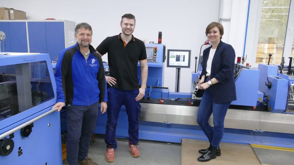 From left: PPL Managing Director Jan Schölzel with Michael and Melanie Nunnenmann at the saddle stitcher equipped with the “PPL Eagle” camera monitoring system.